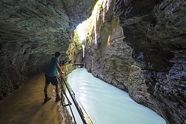 Hiker on walkways admires the creek in the narrow limestone gorge, Aare Gorge, Bernese Oberland, Canton of Uri, Switzerland, Europe