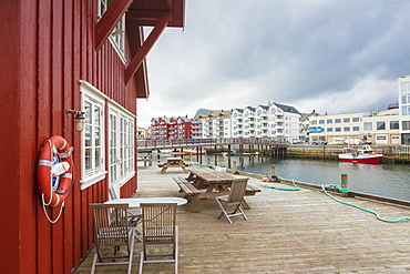 Clouds frame the typical wooden houses of the fishing village surrounded by sea, Svolvaer, Vagan, Lofoten Islands, Norway, Scandinavia, Europe