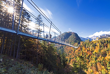 Tourists on the suspension bridge called Highline 179 framed by colorful woods in autumn, Ehrenberg Castle, Reutte, Austria, Europe