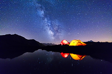 Tents reflected in the alpine lake on a starry night, Mont De La Saxe, Courmayeur, Aosta Valley, Italy, Europe