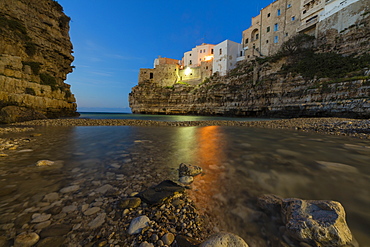 Dusk lights on the clear sea framed by the old town perched on the rocks, Polignano a Mare, Province of Bari, Apulia, Italy, Europe