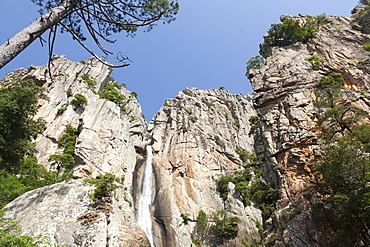 Blue sky frames The Piscia di Gallo waterfall surrounded by granite rocks, Zonza, Southern Corsica, France, Europe