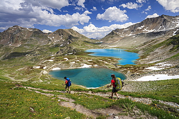 Hikers pass the turquoise lake and rocky peaks, Joriseen, Jorifless Pass, canton of Graubunden, Engadine, Switzerland, Europe