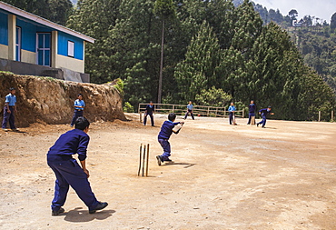 A group of children playing cricket, the national sport of India on a field of dirt on the outskirts of Rimbick, West Bengal, India, Asia