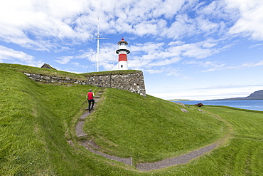 Man walks to the lighthouse and historic fortress of Skansin,Torshavn, Streymoy Island, Faroe Islands, Denmark, Europe