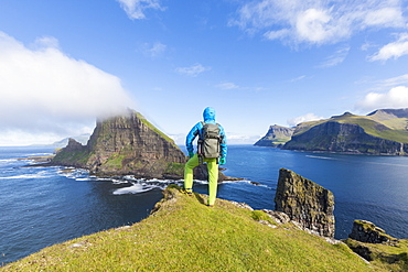 Man looks towards the sea stacks of Drangarnir and Tindholmur islet, Vagar Island, Faroe Islands, Denmark, Europe