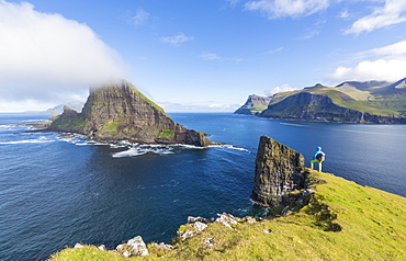 Man looks towards the sea stacks of Drangarnir and Tindholmur islet, Vagar Island, Faroe Islands, Denmark, Europe