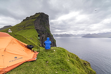 Hiker and tent on cliffs around Kallur Lighthouse, Kalsoy Island, Faroe Islands, Denmark, Europe