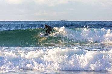 Surfer rides waves, Unstad, Vestvagoy, Lofoten Islands, Nordland, Norway, Europe