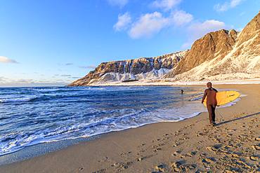 Surfer with surfboard on the beach, Unstad, Vestvagoy, Lofoten Islands, Nordland, Norway, Europe