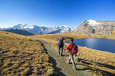 Hikers wallking along Rosset Lake, Gran Paradiso National Park, Alpi Graie (Graian Alps), Italy, Europe