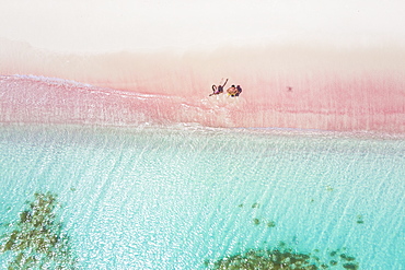 Man and woman having fun to fly a drone on pink sand beach, Caribbean, Antilles, West Indies, Central America