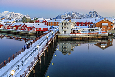 Hikers admire sunset colors on the typical red houses from a deck, Svolvaer, Lofoten Islands, Arctic, Norway, Scandinavia, Europe