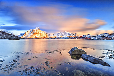 The pink sky at sunrise illuminates Reine village with its cold sea and snowy peaks, Lofoten Islands, Arctic, Norway, Scandinavia, Europe