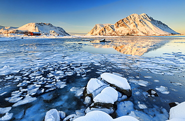 View of the mountains of Gymsoya (Gimsoya) from Smorten reflected in the clear partially frozen sea, Lofoten Islands, Arctic, Norway, Scandinavia, Europe