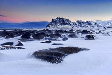 The cold wind that blows constantly shapes the snow on the rocks around Uttakleiv at dawn, Lofoten Islands, Arctic, Norway, Scandinavia, Europe