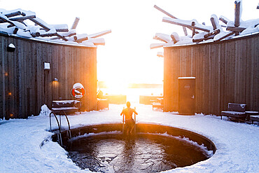 Man enjoying sunset while taking a cold bath in the pool of the Arctic Bath Spa and Wellness Hotel, Harads, Lapland, Sweden, Scandinavia, Europe