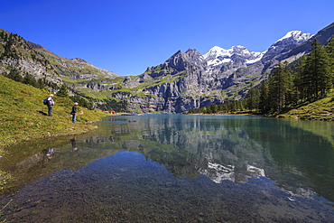 Hikers admire Lake Oeschinensee, Bernese Oberland, Kandersteg, Canton of Bern, Switzerland, Europe