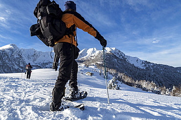 Snowshoe hiker walking in the snowy landscape, Gerola Valley, Valtellina, Orobie Alps, Lombardy, Italy, Europe