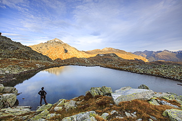 Hiker admires Lake Bergsee at sunrise, Chiavenna Valle, Spluga Valley, Switzerland, Europe