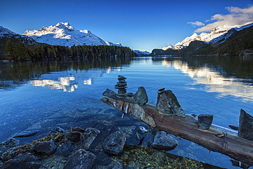 Dawn illuminates the snowy peaks reflected in the calm waters of Lake Sils, Engadine, Canton of Graubunden, Switzerland, Europe