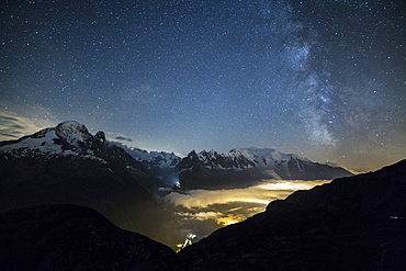 Stars and Milky Way illuminate the snowy peaks around Lac de Cheserys, Chamonix, Haute Savoie, French Alps, France, Europe