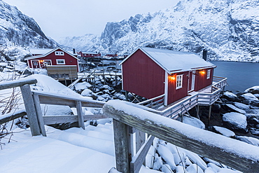 Typical fishermen houses called rorbu in the snowy landscape at dusk, Nusfjord, Nordland County, Lofoten Islands, Norway, Scandinavia, Europe