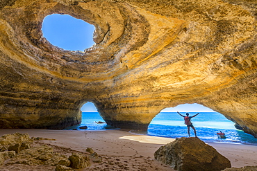 A tourist inside the sea caves of Benagil admires the clear waters of the Atlantic Ocean, Faro District, Algarve, Portugal, Europe