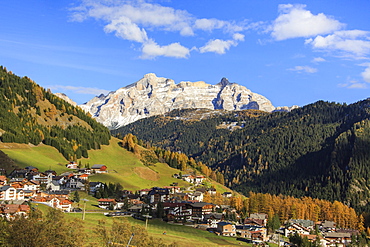 Colourful woods frame the village and the high peaks in autumn, Gardena Pass, South Tyrol, Trentino-Alto Adige, Italy, Europe