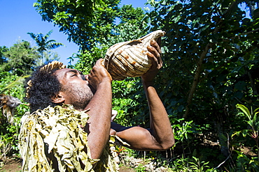 Man blowing in a giant shell, Ekasup Cultural Village, Efate, Vanuatu, Pacific