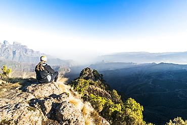 Woman enjoying the early morning sun on the cliffs, Simien Mountains National Park, UNESCO World Heritage Site, Debarq, Ethiopia, Africa