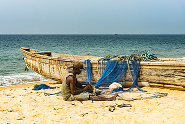 Man fixing their nets in their fishing boats on a beach in Robertsport, Liberia, West Africa, Africa