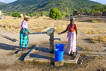 Women pumping water out of a well at Lake Malawi, Cape Maclear, Malawi, Africa