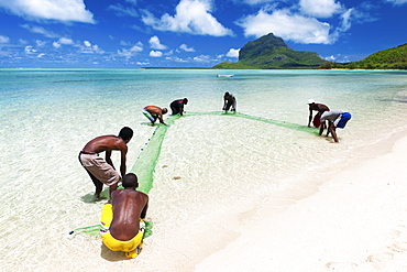 Fisherman on a beach being overlooked by the basaltic monolith, Le Morne, Black River, Mauritius, Indian Ocean, Africa