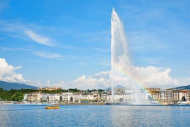 Yellow water taxi ???Mouettes genevoises??? on the calm waters of Lake Geneva with tourist attraction Jet d'eau in the background