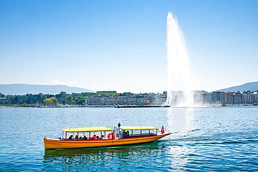 Yellow water taxi ???Mouettes genevoises??? on the calm waters of Lake Geneva with tourist attraction Jet d'eau in the background