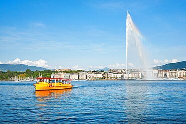 Yellow water taxi ???Mouettes genevoises??? on the calm waters of Lake Geneva with tourist attraction Jet d'eau in the background