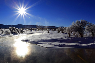 Winter landscape with hoarfrost, steaming river, brilliant sunshine and blue sky, utah, usa