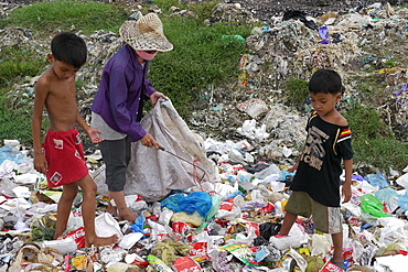 CAMBODIA Scavenger Soun Srey Thouch searching for recyclable materials on Phnom Penh's Mean Caeay garbage dump, with sons Khoeun Sovan (8) and Khoeun Sanja (10)