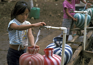 Guatemala girls drawing water standpipe at a resettlement project in the peten