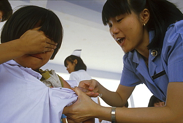 Thailand nurse giving a school an immunisation, chiang mai