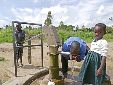 UGANDA Children collecting water from hand-pumped bore well, Gulu. PHOTO by Sean Sprague