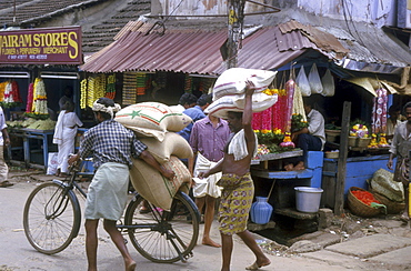 India - transportation carrying sacks of in a market street trivandrum, kerala