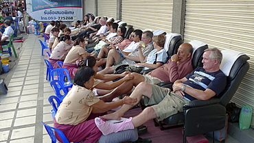 THAILAND Chiang Mai.Tourists getting foot and leg massage in the street. Photo by Sean Sprague