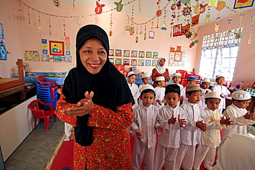 Indonesia a kindergarten in banda aceh which lost many of children to tsunami, been rebuilt. schools director halimah anwar bustam (seen here in foreground) describes horrors suffered: area kids came from completely flattened by waves. On that fateful sunday children were in their homes, or many were already on beach having. So many died that morning. It devastating. Only we getting things back together, very grateful to helping with reconstruction of damaged building. staff give up a portion of their (already) salaries to sponsor poor children from outlying villages to come to school. structure includes offices staff, a library, prayer room wheelchair accessible classroom.__ Photograph taken in banda aceh, -december 2006, 2 years after tsunami of december 26th 2004 devasted much of coastal region. Taken to illustrate reconstruction work projects of (catholic relief services) of sponsored photo tour 