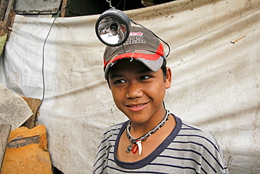 Philippines boy wearing a headlamp. He is getting ready to scavenge on the dump. Shantytown dwelling near garbage tip at bagong silangan, quezon city, manila