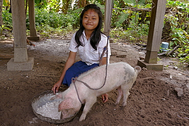 CAMBODIA Lum Thong Khan, 13, at home, Kamphun village, Stung Treng district. Feeding pig