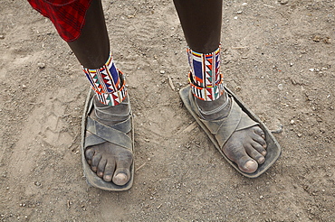 Kenya. Detail of sandals made from car tires and ankle ornaments worn by a masai warrior, masai village within the amboseli national park