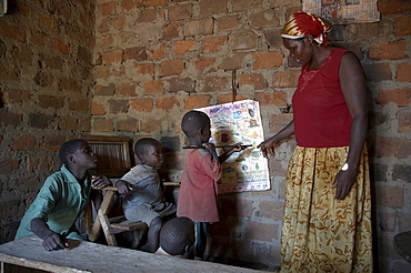 Uganda in the home of najjemba teopista, caritas lugazi agricultural field animator, kasaayi village, kayunga district. teopista teaching her children the abcs