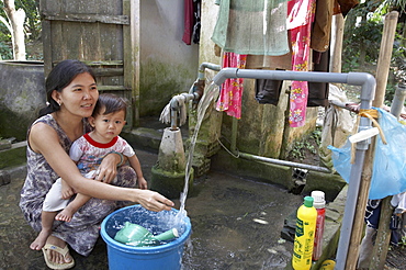 Vietnam community water purifying project in village of tam phu, tam pinh district in vinh long province. previously the community would take water directly from a canal, for drinking. thanks to this project, they now have safe drining water. fran thi bich ngoc and her child vo truong vy, taking safe drinking water from a faucet in their home